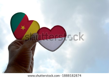 Hand holds a heart Shape Cameroon and Indonesia flag, love between two countries