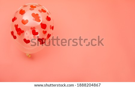 Transparent balloon with a print in the shape of a heart on a pink background. Valentine's day background, top view. Place for text.
