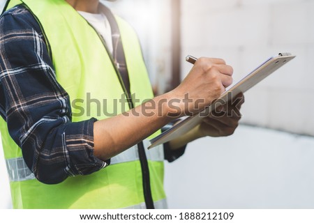 close up hands of inspector waer safety vest and checking list into clipboard Royalty-Free Stock Photo #1888212109