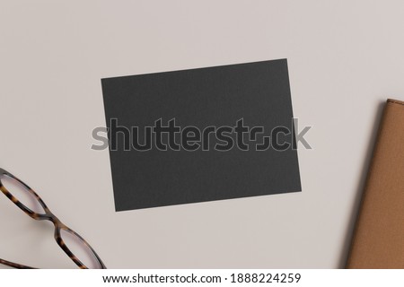 Black invitation card mockup with a glasses and a notebook. Workspace concept. 5x7 ratio, similar to A6, A5.