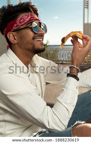 Young guy eating pizza. outside. selective focus