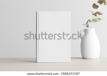 White book mockup with a eucalyptus in a vase on a beige table. Royalty-Free Stock Photo #1888241587