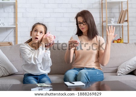 Financial crisis during coronavirus pandemic concept. Teen girl with empty piggy bank and young mother with no money to pay bills at home, having problems with family budget Royalty-Free Stock Photo #1888269829
