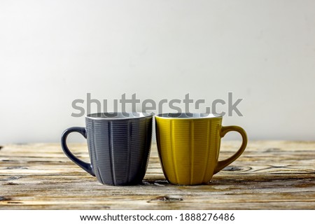 Two cups of tea in trendy colors Ultimate Gray and Illuminating on a wooden table