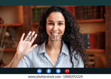 Head shot of smiling young female employee worker waving hand to webcam, greeting colleagues at remote brainstorm online meeting, woman using computer video call software app, laptop screen view Royalty-Free Stock Photo #1888292224