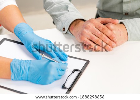 A gloved dermatologist examines the skin of a sick patient and records observations. Examination and diagnosis of skin diseases-allergies, psoriasis, eczema, dermatitis. Royalty-Free Stock Photo #1888298656