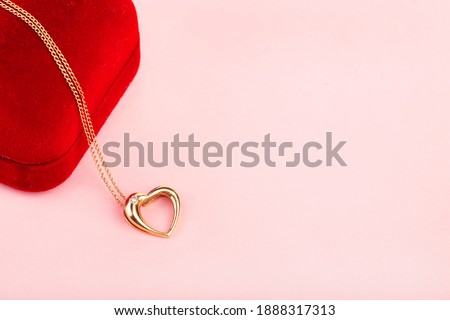 gold heart shaped pendant on red box, pink background, valentine's day, gift Royalty-Free Stock Photo #1888317313