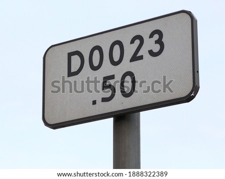 Photo shows a road sigh showing a set of numbers and a letter D.