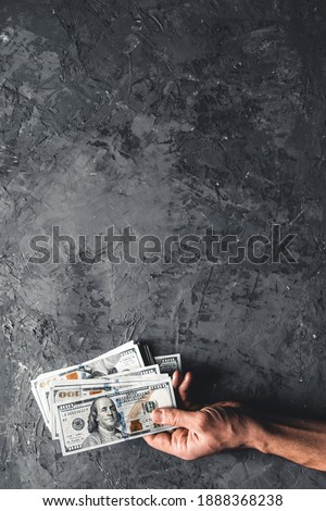 Hand holding money against dark background. Business concept, development perspective.