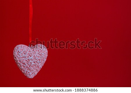 pink heart of roses on a ribbon on a red background. Space for notes and inscriptions