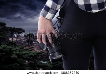 Female photographer or tourist with a photography hobby looking at the ocean landscape of the California coastline.  It is cloudy and there is a coming storm