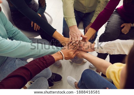 Mixed race people sitting in circle and putting hands together in business team meeting or group therapy session. Community, trust, success, motivation, mutual responsibility, unity, support concepts Royalty-Free Stock Photo #1888418581
