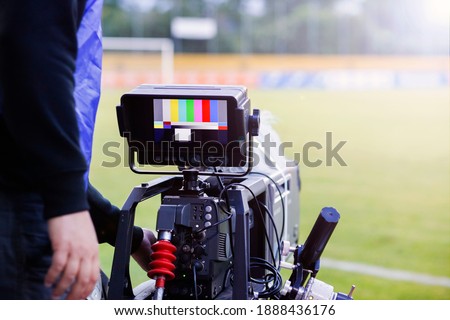 Television broadcast camera shooting at a sunny football game