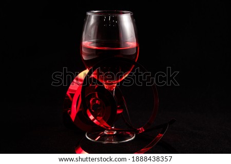 Single wine glass with Valentine hearts against a black background.