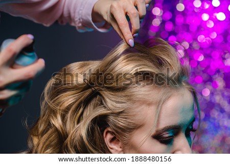 Stylist makes girl's hair. Combing female hair. Hair care for woman. Stylist makes an evening hairstyle for model at photo shoot.