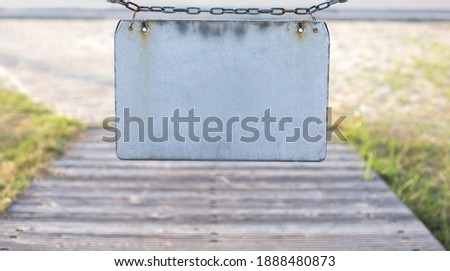 Close up gray blank plate on chain at street background, no way sign, place for text and design 