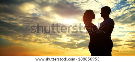 Silhouettes of a young couple lovers at sunset in rays of setting sun. banner
