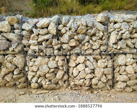 Large boulders tied with wire mesh to prevent landslides.