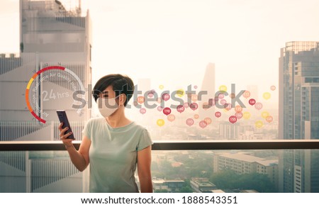 An asian woman use her smartphone application checking real-time Air Quality at the balcony outside the building. The data show the air in Bangkok city is very poor and unhealthy to breath. PM 2.5  Royalty-Free Stock Photo #1888543351