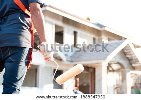 The young construction contractor plans to paint a big house. Royalty-Free Stock Photo #1888547950