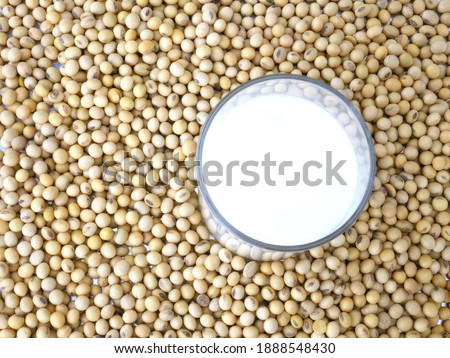 Soy milk in glass on soybeans background.
