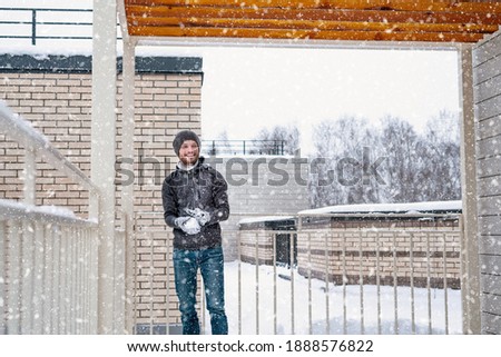 Snow battle. A middle aged man throwing a snowball. Dad and son playing snowballs during the snowfall. Outdoor winter family activity