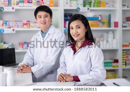 Two Male and female pharmacists smiling happy to Service in drugstore Thailand health care and business concept 