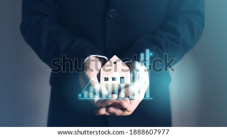 Business realtor man hand holding home model with digital finance graph increase. Property investment and insurance concept.  Royalty-Free Stock Photo #1888607977