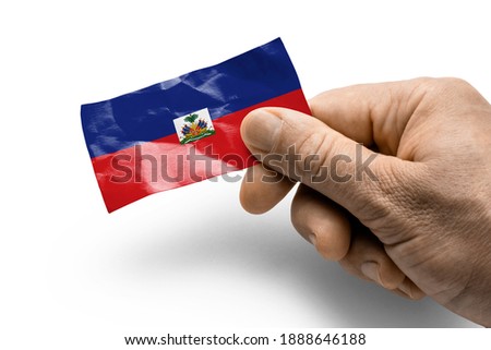 Hand holding a card with a national flag the Haiti