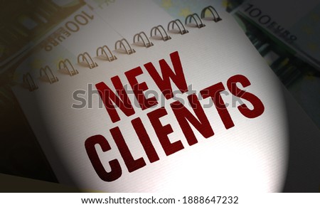 New clients words on the page of Copybook put on 100 Euro banknotes. Selective focus. Business concept.
