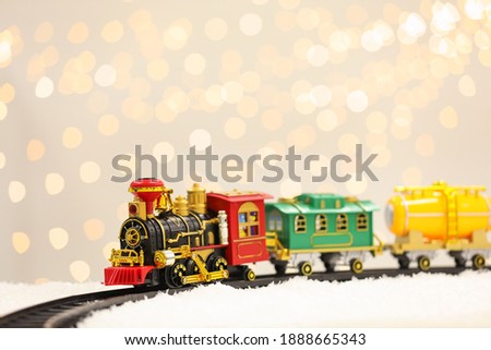 Toy train and railway on snow against Christmas lights