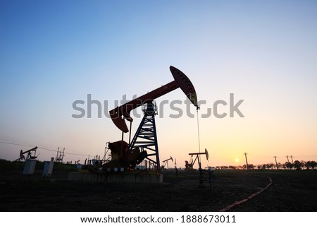 In the field, the oil pump in the evening, the evening silhouette of the pumping unit, the silhouette of the oil pump