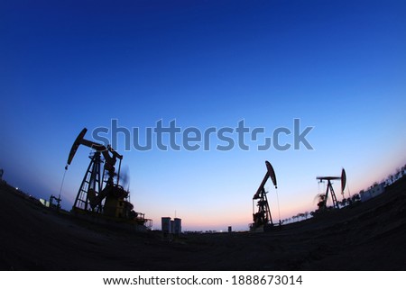 In the field, the oil pump in the evening, the evening silhouette of the pumping unit, the silhouette of the oil pump