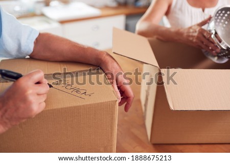 Close Up Of Senior Couple Downsizing In Retirement Boxes Ready For Move Into New Home Royalty-Free Stock Photo #1888675213