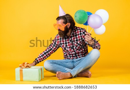 open gift. hipster smiling happily. having fun on party. prepare for holidays. Event manager poses with festive accessory. fun and happiness concept. happy man holding colorful helium balloons.