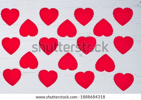 Top view of small red hearts made of paper evenly lined on a white old wooden background .Concept of texture, valentines day.                         