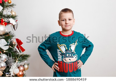 smiling nine-year-old boy in green pajamas with a picture of a cow. happy new year. year of the cow. Chinese New Year