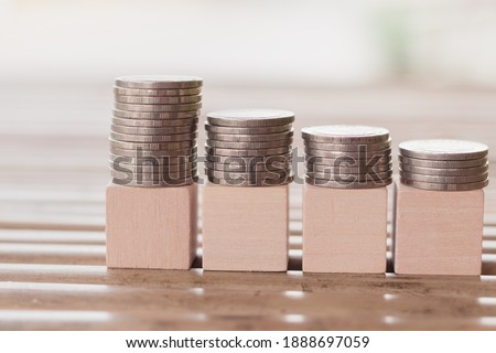 The wood block on stacks of coins and four wooden blocks with nature background for design or art work to insert text or word, Education, Business,Saving money or banking concept, Selective focus.