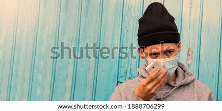 man with disposable surgical mask talking on the smartphone