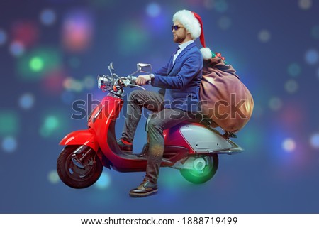 Christmas and New Year. Handsome man in elegant suit and Santa's hat sits on a red scooter with gifts. Blue background with festive lights.