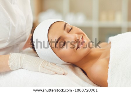 Beautiful young woman receiving skin treatment from a beautician. Smiling young womans face with clsed eyes expressing happiness during skincare procedure in beauty spa salon Royalty-Free Stock Photo #1888720981