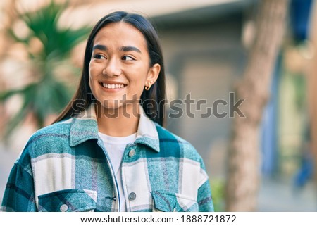 Young latin girl smiling happy standing at the city.