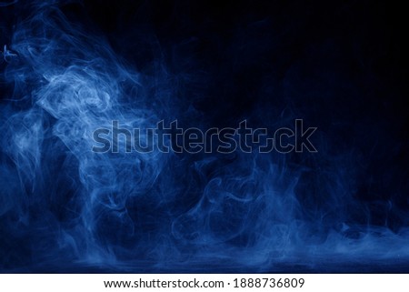Abstract blue smoke moves on black background. Mystical swirling smoke rolling low across the ground.
