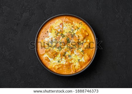 Murgh Makhani or Butter Chicken in black bowl on dark slate table top. Indian Cuisine dish with chicken meat and creamy masala. Asian food and meal. Top view Royalty-Free Stock Photo #1888746373