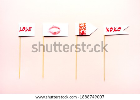Valentine's day props on a pink surface. Pink background. The words of love and the imprint of lips are written on the flags