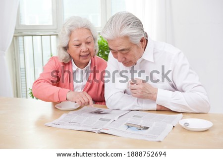 The happy old couple are reading the newspaper high quality photo