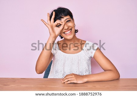 Beautiful brunettte woman wearing casual clothes over pink background smiling happy doing ok sign with hand on eye looking through fingers 