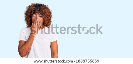 Young african american woman wearing casual white tshirt bored yawning tired covering mouth with hand. restless and sleepiness. 