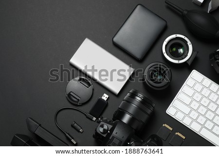 Camera, video production equipment and computer keyboard on black background, flat lay