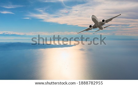 Airplane flying over tropical sea at sunset Royalty-Free Stock Photo #1888782955